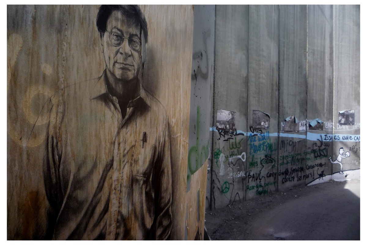 A portrait of the poet Mahmoud Darwish painted on the separation wall in Bethlehem, photographed in 2010. Photo: symmetry_mind, via Wikimedia Commons, CC BY-SA 2.0.